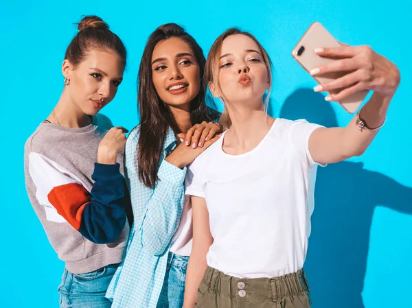 3个穿着夏装的年轻嬉皮士女人 女孩们用智能手机自拍自画像 模特们在研究中靠墙摆姿势 女人们在正面相机上做鸭脸 — 图库照片
