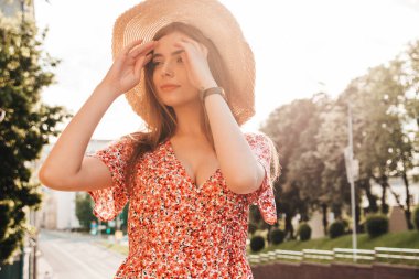 Yaz hippi elbisesi giymiş güzel gülümseyen bir mankenin portresi. Günbatımında sokakta poz veren tasasız bir kız. Şapkalı, modaya uygun, komik ve pozitif bir kadın.