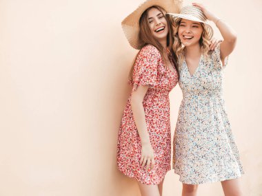 İki güzel, gülümseyen yeniyetme kız şık yaz kıyafetleri içinde. Sokakta şapkalarla poz veren kaygısız kadınlar. Pozitif modeller eğleniyor ve sarılıyorlar.