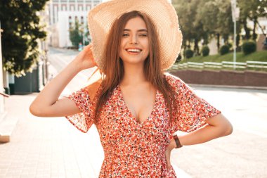 Genç, güzel, güler yüzlü yeniyetme bir kızın son moda bir yaz elbisesi içinde portresi. Günbatımında sokakta poz veren kaygısız bir kadın. Açık havada pozitif model.