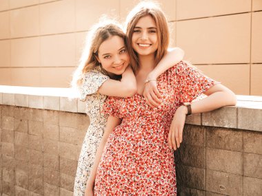 İki güzel, gülümseyen yeniyetme kız şık yaz kıyafetleri içinde. Sokakta poz veren kaygısız kadınlar. Pozitif modeller eğleniyor ve deliriyor.