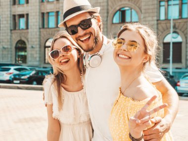 Sokakta poz veren üç genç arkadaş grubu. Moda adamı ve sıradan yaz kıyafetleri giymiş iki tatlı kız. Gülümseyen mankenler güneş gözlükleriyle eğleniyorlar. Neşeli kadınlar ve erkekler çıldırıyor.