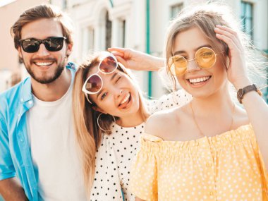 Sokakta poz veren üç genç arkadaş grubu. Moda adamı ve sıradan yaz kıyafetleri giymiş iki tatlı kız. Gülümseyen modeller güneş gözlükleriyle eğleniyorlar. Neşeli kadınlar ve Susnet 'teki adam.