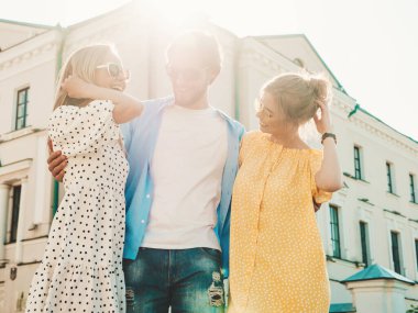 Sokakta poz veren üç genç arkadaş grubu. Moda adamı ve sıradan yaz kıyafetleri giymiş iki tatlı kız. Gülümseyen modeller güneş gözlükleriyle eğleniyorlar. Neşeli kadınlar ve Susnet 'teki adam.