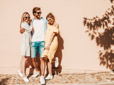 Sokakta poz veren üç genç arkadaş grubu. Moda adamı ve sıradan yaz kıyafetleri giymiş iki tatlı kız. Gülümseyen mankenler güneş gözlükleriyle eğleniyorlar. Neşeli kadınlar ve erkekler çıldırıyor.