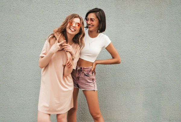 流行の夏服の2人の若い美しい笑顔ヒップスターの女の子 サングラスで通りの背景にポーズ性的屈託のない女性 楽しさと抱擁を持つ肯定的なモデル — ストック写真