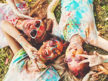 Yaz mevsiminde Holi Renk Festivali 'nde parti veren üç mutlu güzel kız. Gün batımında müzik etkinliği sonrasında gülümseyen genç bayan arkadaşlar. Güneş gözlüğüyle çimlerin üzerinde yatan mankenler.