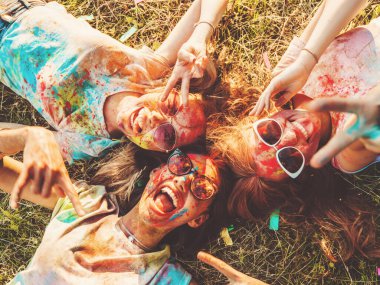 Yaz mevsiminde Holi Renk Festivali 'nde parti veren üç mutlu güzel kız. Gün batımında müzik etkinliği sonrasında gülümseyen genç bayan arkadaşlar. Güneş gözlüğüyle çimlerin üzerinde yatan mankenler.