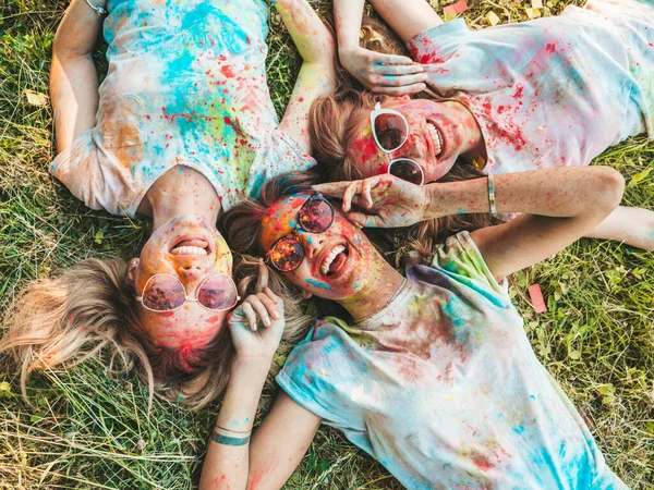 Yaz mevsiminde Holi Renk Festivali 'nde parti veren üç mutlu güzel kız. Gün batımında müzik etkinliği sonrasında gülümseyen genç bayan arkadaşlar. Güneş gözlüğüyle çimlerin üzerinde yatan mankenler.