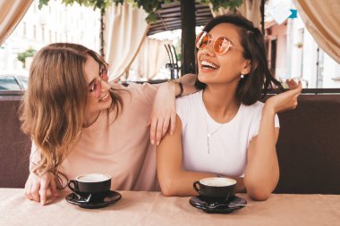 Son moda yaz kıyafetleri içinde gülümseyen iki genç hippi kız. Veranda kafesinde sohbet eden ve kahve içen kaygısız kadınlar. Pozitif modeller eğleniyor ve iletişim kuruyor.