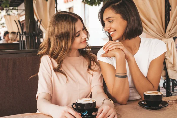 Son moda yaz kıyafetleri içinde gülümseyen iki genç hippi kız. Veranda kafesinde sohbet eden ve kahve içen kaygısız kadınlar. Pozitif modeller eğleniyor ve iletişim kuruyor.