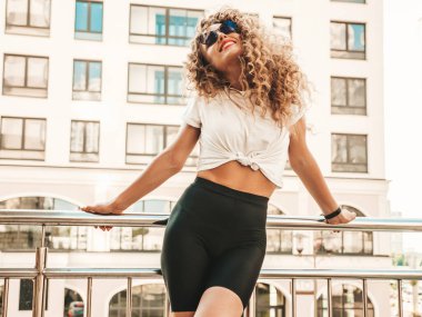 Kıvırcık saçlı, yaz hippi kıyafetleri giymiş, güzel gülümseyen mankenin portresi. Sokakta poz veren kaygısız kız. Modayı takip eden eğlenceli ve olumlu kadın.