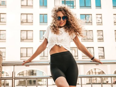 Kıvırcık saçlı, yaz hippi kıyafetleri giymiş, güzel gülümseyen mankenin portresi. Sokakta poz veren kaygısız kız. Modayı takip eden eğlenceli ve olumlu kadın.