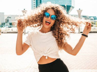 Kıvırcık saçlı, yaz hippi kıyafetleri giymiş, güzel gülümseyen mankenin portresi. Sokakta poz veren kaygısız kız. Modayı takip eden eğlenceli ve olumlu kadın.