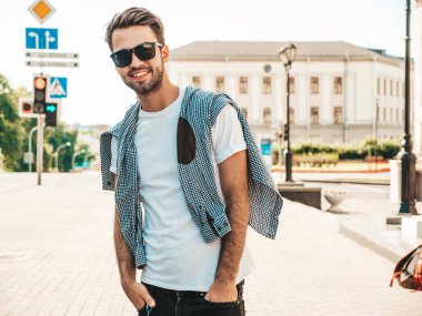 Yakışıklı, gülümseyen stil sahibi Lambersex modelinin portresi. Beyaz tişört giyen adam. Sokakta güneş gözlükleriyle poz veren modacı erkek.