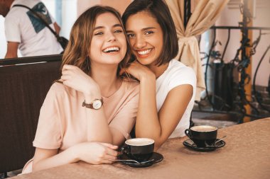 Son moda yaz kıyafetleri içinde gülümseyen iki genç hippi kız. Veranda kafesinde sohbet eden ve kahve içen kaygısız kadınlar. Pozitif modeller eğleniyor ve iletişim kuruyor.