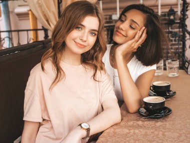 Son moda yaz kıyafetleri içinde gülümseyen iki genç hippi kız. Veranda kafesinde sohbet eden ve kahve içen kaygısız kadınlar. Pozitif modeller eğleniyor ve iletişim kuruyor.