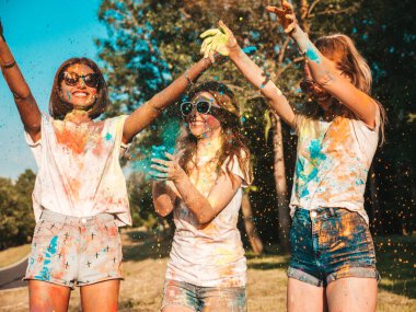 Yaz mevsiminde Holi Renk Festivali 'nde parti veren üç mutlu güzel kız. Gün batımında müzik olayından sonra gülümseyen genç bayan arkadaşlar eğleniyor. Gün batımında güneş gözlükleriyle çıldıran pozitif modeller.