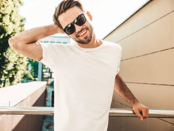 Yakışıklı, gülümseyen stil sahibi Lambersex modelinin portresi. Beyaz tişört giyen adam. Dışarıda güneş gözlüklü, sokakta poz veren modacı erkek.