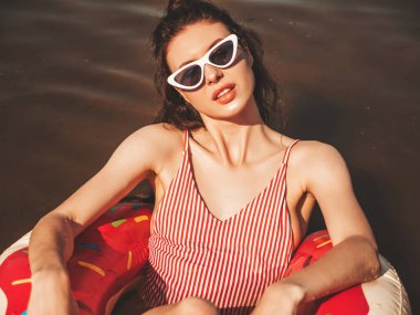 Güneş gözlüklü genç, güzel, seksi hippi kadın. Mayo giyen kız mayo giyiyor, yüzüyor ve lilo şişirilebilir şilteler içinde yatıyor. Gölde dinlenen pozitif kadın.