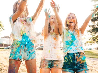 Yaz mevsiminde Holi Renk Festivali 'nde parti veren üç mutlu güzel kız. Gün batımında müzik etkinliğinden sonra gülümseyen genç bayan arkadaşlar eğleniyor. Güneş batarken güneş gözlükleriyle çıldıran pozitif modeller.
