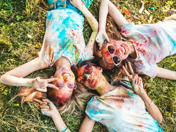 在夏天的荷莉彩色节上 三个快乐而美丽的女孩正在举行派对 在夕阳西下的音乐活动之后 年轻的微笑的女性朋友们正在享受快乐 — 图库照片