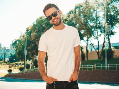 Yakışıklı, gülümseyen stil sahibi Lambersex modelinin portresi. Beyaz tişört giyen adam. Dışarıda güneş gözlüklü, sokakta poz veren modacı erkek.