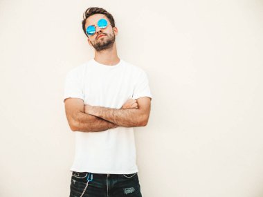 Yakışıklı, kendine güvenen, stil sahibi, Lambersex mankeni portresi. Beyaz tişört giyen adam. Moda erkek, dışarıda güneş gözlüklü, duvarın yanında poz veriyor.