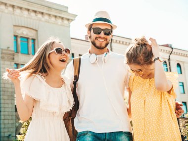 Sokakta poz veren üç genç arkadaş grubu. Moda adamı ve sıradan yaz kıyafetleri giymiş iki tatlı kız. Gülümseyen mankenler güneş gözlükleriyle eğleniyorlar. Neşeli kadınlar ve erkekler çıldırıyor.