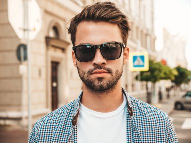 Yakışıklı, kendine güvenen, stil sahibi bir hipster Lambersex modelinin portresi. Gömlek giymiş bir adam. Sokakta güneş gözlükleriyle poz veren modacı erkek.