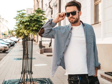 Yakışıklı, kendine güvenen, stil sahibi bir hipster Lambersex modelinin portresi. Gömlek giymiş bir adam. Sokakta güneş gözlükleriyle poz veren modacı erkek.