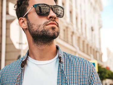 Yakışıklı, kendine güvenen, stil sahibi bir hipster Lambersex modelinin portresi. Gömlek giymiş bir adam. Sokakta güneş gözlükleriyle poz veren modacı erkek.