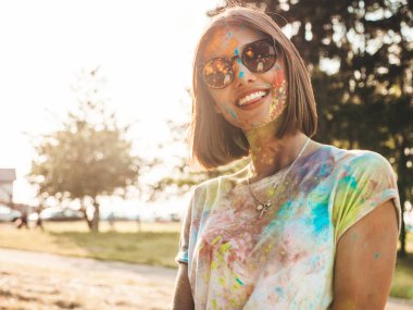 Yazın Holi Renk Festivali 'nde parti veren mutlu güzel kız. Gün batımında müzik olayından sonra gülümseyen genç kadın eğleniyor. Gün batımında güneş gözlüklü pozitif model