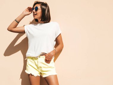 Yazın hippi kıyafetleri içinde gülümseyen güzel esmer modelin portresi. Duvarın yanında poz veren moda bir kız. Eğlenceli ve olumlu kadın eğleniyor.