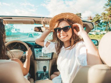 Üstü açık arabadaki güzel ve gülümseyen hippi kız portresi. Cabriolet kullanan kaygısız seksi kadın. Pozitif model sürüş ve güneş gözlüğü ve şapkayla eğlenme