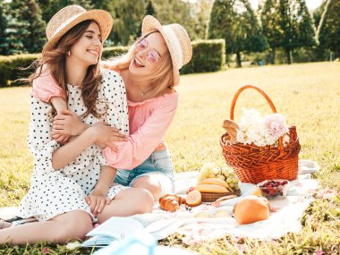 İki güzel hippi kadın, son moda yaz elbisesi ve şapkaları içinde. Kaygısız kadınlar dışarıda piknik yapıyor. Olumlu modeller çimlerin üzerinde oturmuş, meyve ve peynir yiyorlar.