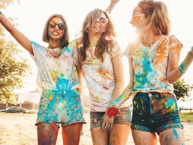 Yaz mevsiminde Holi Renk Festivali 'nde parti veren üç mutlu güzel kız. Gün batımında müzik etkinliğinden sonra gülümseyen genç bayan arkadaşlar eğleniyor. Güneş batarken güneş gözlükleriyle çıldıran pozitif modeller.