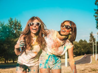 Yazın Holi Renk Festivali 'nde parti yapan iki mutlu güzel kız. Gün batımında müzik etkinliğinden sonra gülümseyen genç bayan arkadaşlar eğleniyor. Güneş batarken güneş gözlükleriyle çıldıran pozitif modeller.