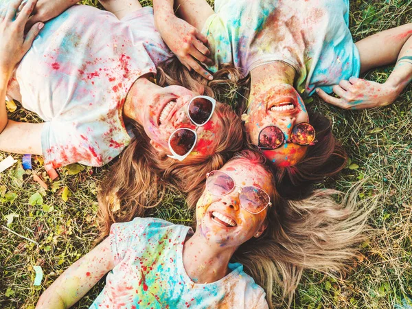 在夏天的荷莉彩色节上 三个快乐而美丽的女孩正在举行派对 在夕阳西下的音乐活动之后 年轻的微笑的女性朋友们正在享受快乐 — 图库照片