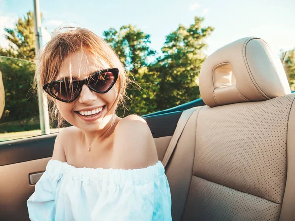 Üstü açık arabadaki güzel ve gülümseyen hippi kız portresi. Cabriolet kullanan kaygısız seksi kadın. Gün batımında güneş gözlüğüyle gezmek ve eğlenmek