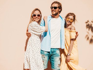 Sokakta poz veren üç genç arkadaş grubu. Moda adamı ve sıradan yaz kıyafetleri giymiş iki tatlı kız. Gülümseyen mankenler güneş gözlükleriyle eğleniyorlar. Neşeli kadınlar ve erkekler çıldırıyor.