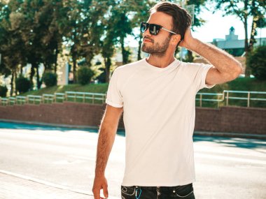 Yakışıklı, gülümseyen stil sahibi Lambersex modelinin portresi. Beyaz tişört giyen adam. Sokakta güneş gözlükleriyle poz veren modacı erkek.