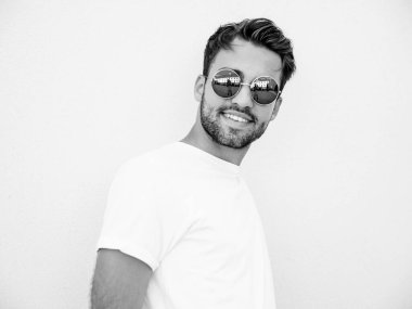 Yakışıklı, kendine güvenen, stil sahibi, Lambersex mankeni portresi. Beyaz tişört giyen adam. Moda erkek, dışarıda güneş gözlüklü, duvarın yanında poz veriyor.