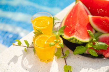 Yaz tatili tropikal kavramı. Yüzme havuzu sınırında taze portakal suyu ve karpuz suyu ve ananas.