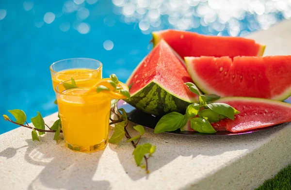 Conceito tropical de férias de verão. Sumo de laranja fresco e suco de melancia e abacaxi na borda de uma piscina . — Fotografia de Stock