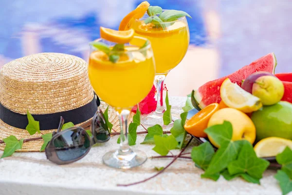 Copa de licuado de jugo fresco de sandía con flores, gafas de sol, zapatillas y sombrero de paja en el borde de una piscina - concepto tropical de vacaciones — Foto de Stock