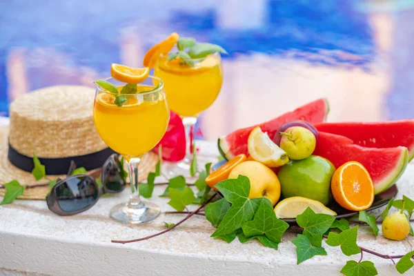 Copa de licuado de jugo fresco de sandía con flores, gafas de sol, zapatillas y sombrero de paja en el borde de una piscina - concepto tropical de vacaciones — Foto de Stock