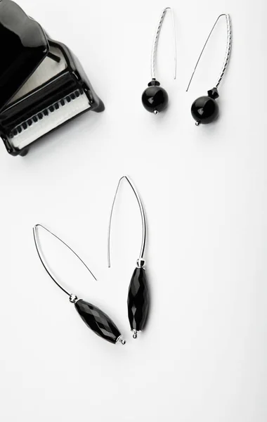 シルバー イヤリング黒瑪瑙石白い背景のおもちゃのピアノ — ストック写真
