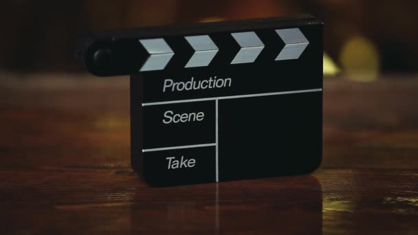 Clapperboard Мокрый Деревянный Стол Золото Bokeh Кадры — стоковое видео