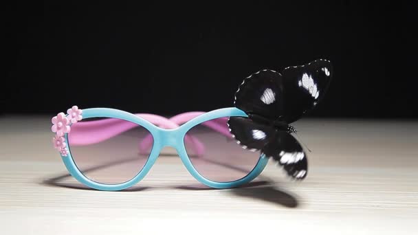 Sonnenbrille Schmetterling Holztisch Dunklen Hintergrund Filmmaterial — Stockvideo
